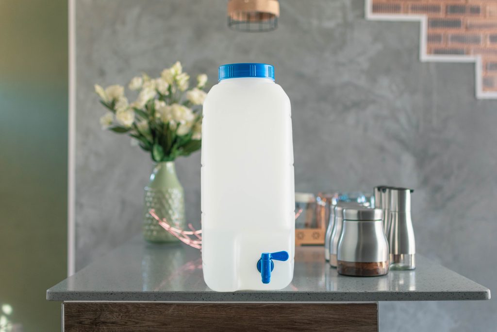 A refillable water container with a blue tap on a kitchen counter, promoting the benefits of water refilling services.