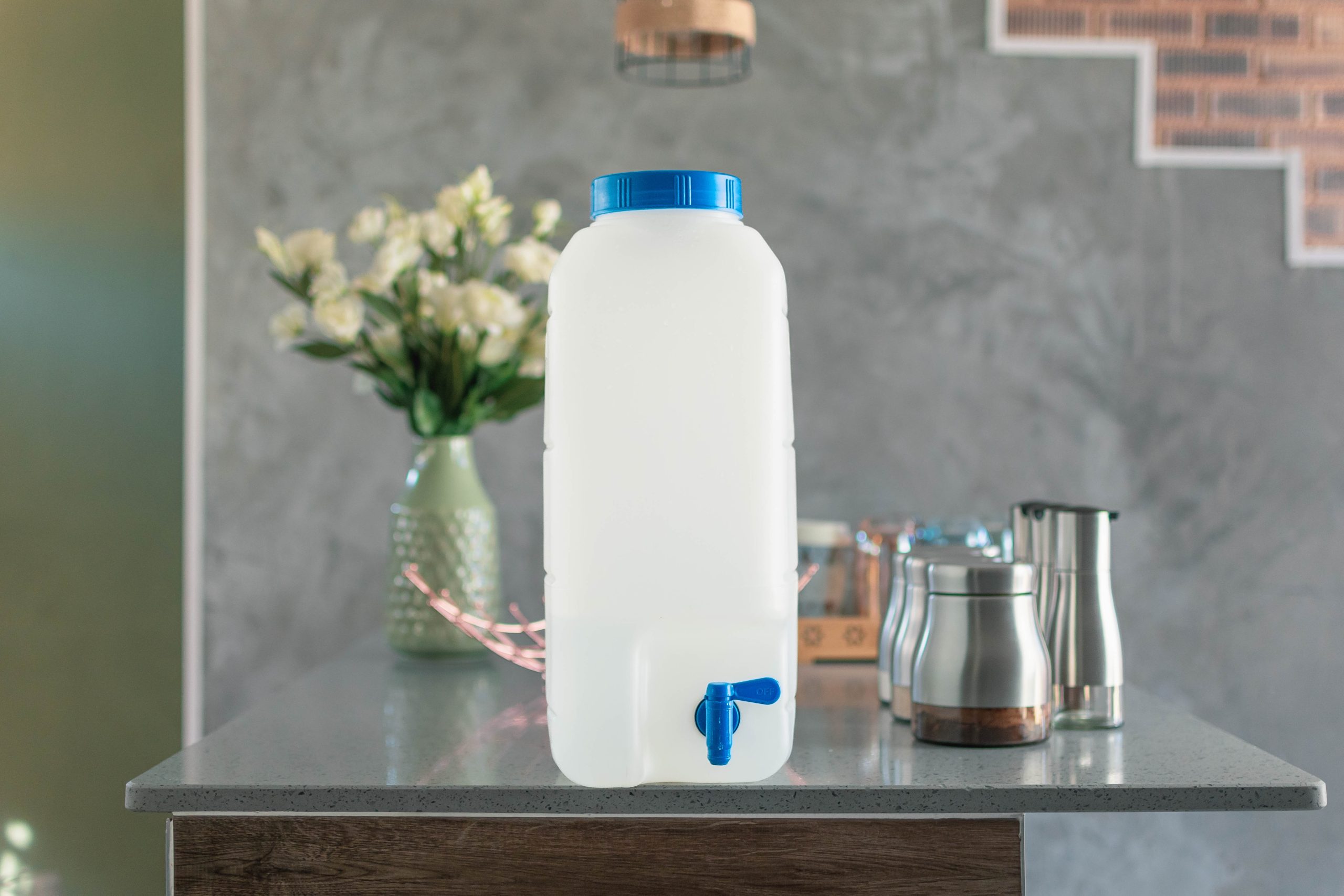 A refillable water container with a blue tap on a kitchen counter, promoting the benefits of water refilling services.